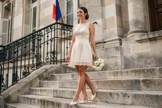 Jeune mariée en robe courte en dentelle ivoire sur les marches d'une mairie française pour un mariage civil