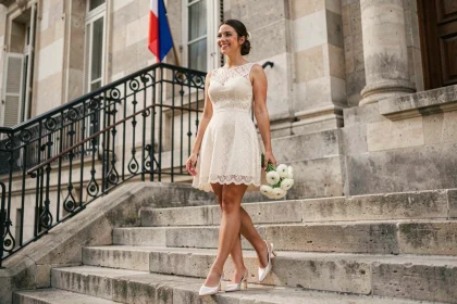 Jeune mariée en robe courte en dentelle ivoire sur les marches d'une mairie française pour un mariage civil
